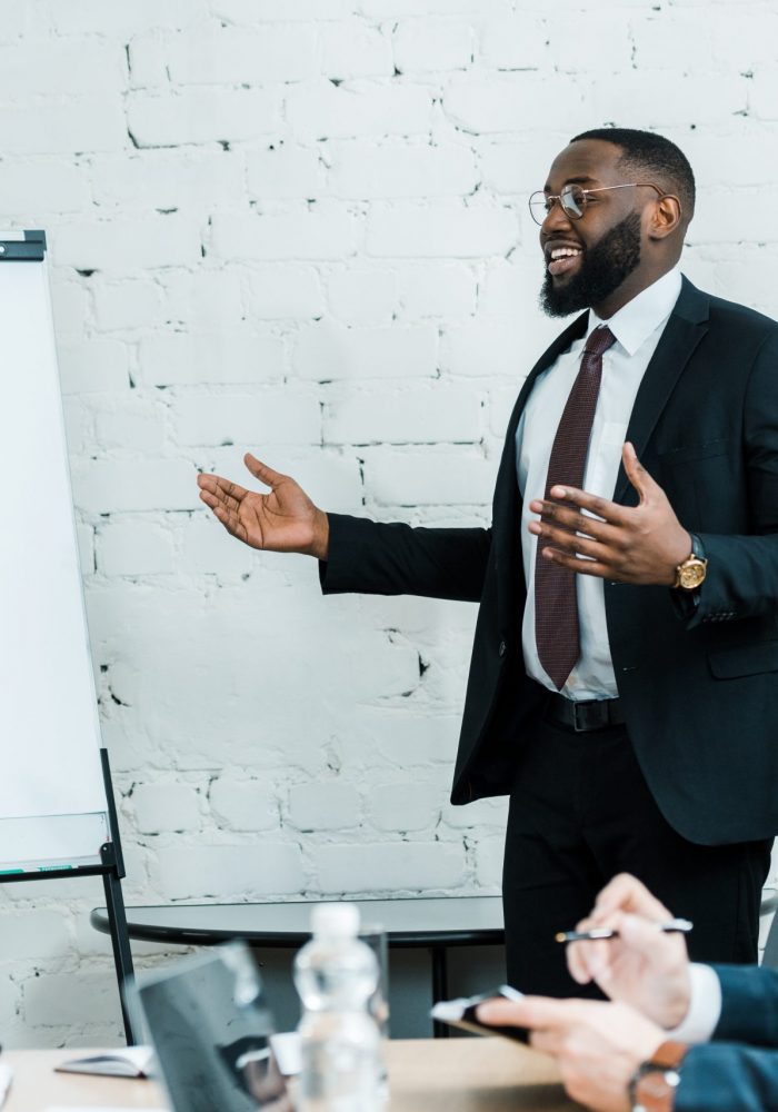 happy african american business coach talking near white board and colleague
